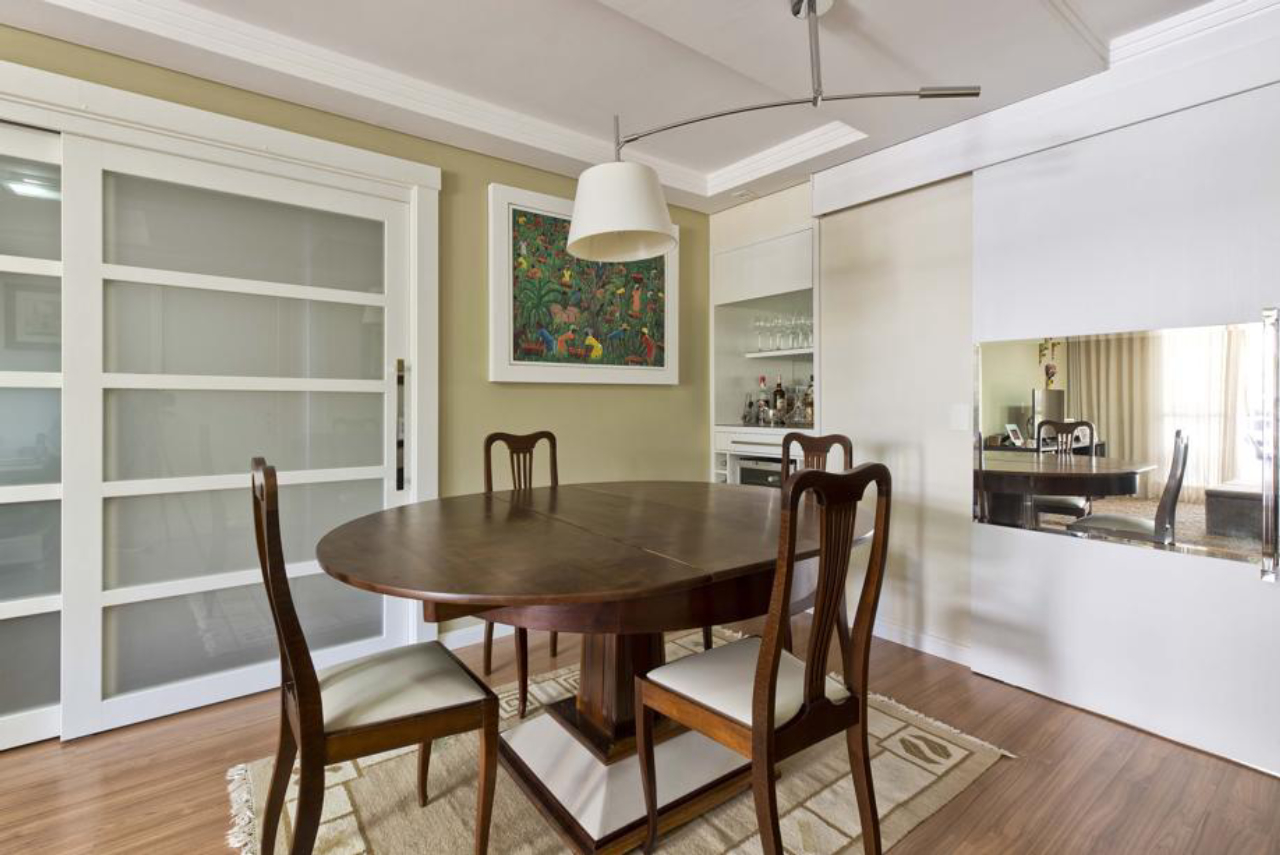 Feita sob medida em marcenaria e vidro, a porta painel dá o tom bucólico à sala de jantar composta pela arquiteta Monica Raeder. Foto: Marcelo Stammer/Divulgação