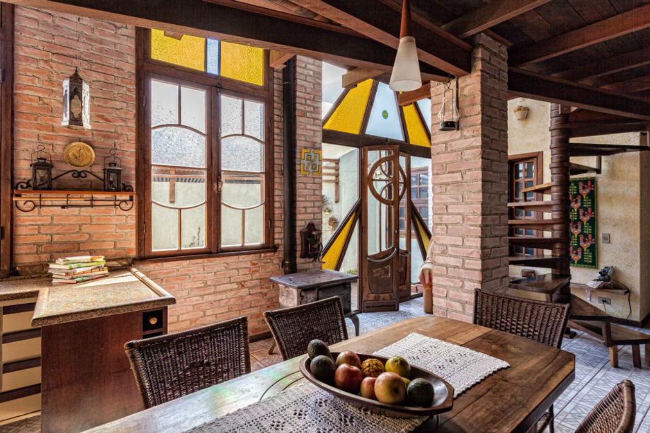 Cozinha da casa dos Amorim tem portas de janelas de demolição e um fogão a lenha antigo. Acima, parede com os violinos construídos por Luiz e a parede com pintura de cal. Foto: Fernando Zequinão/Gazeta do Povo