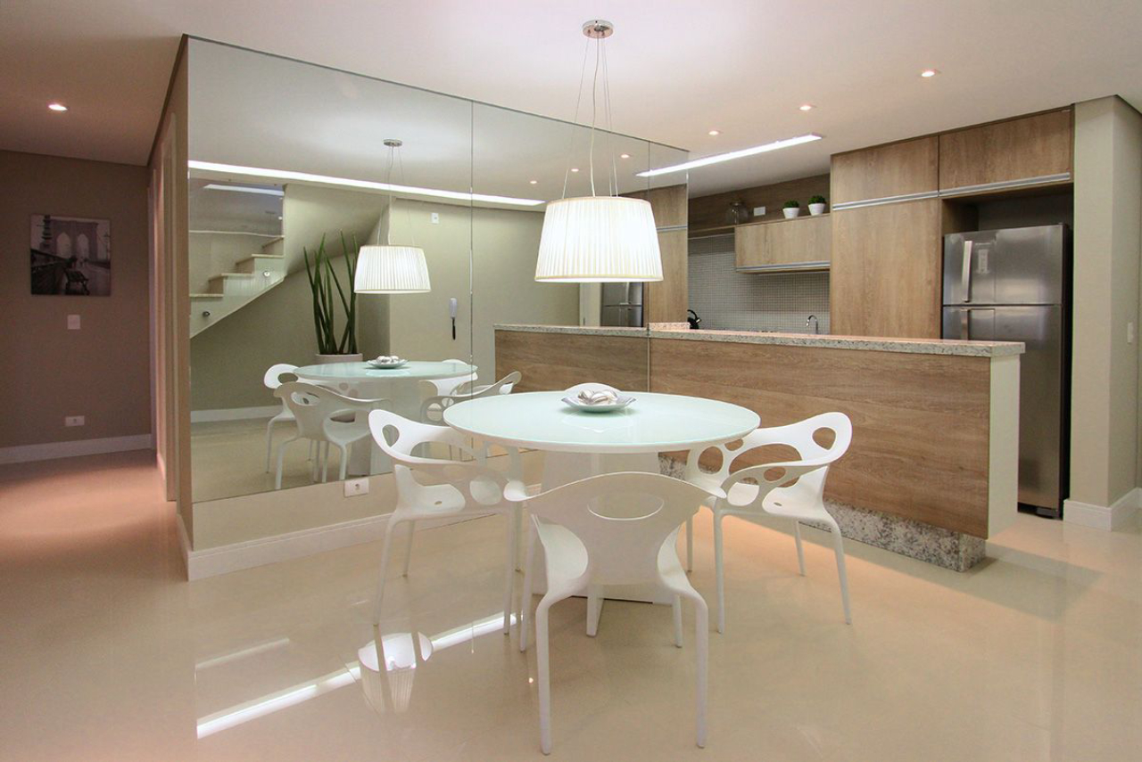 Mesa redonda e cadeiras de design contemporâneo pontuam a cozinha e copa integradas. 