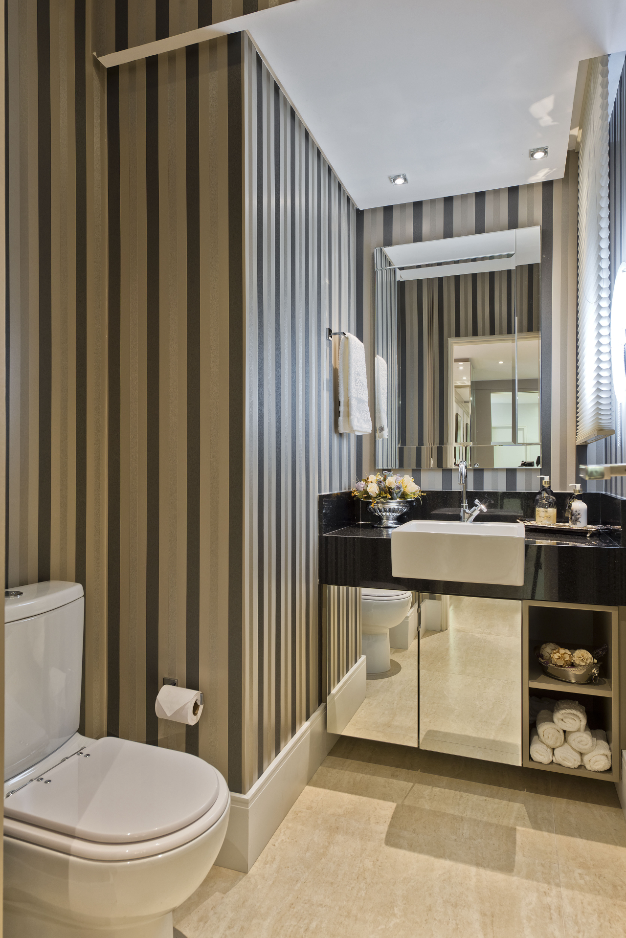 No lavabo foi usado papel de parede e muito espelho para descaracterizar o padrão de banheiro e aproximá-lo da decoração da área social.  