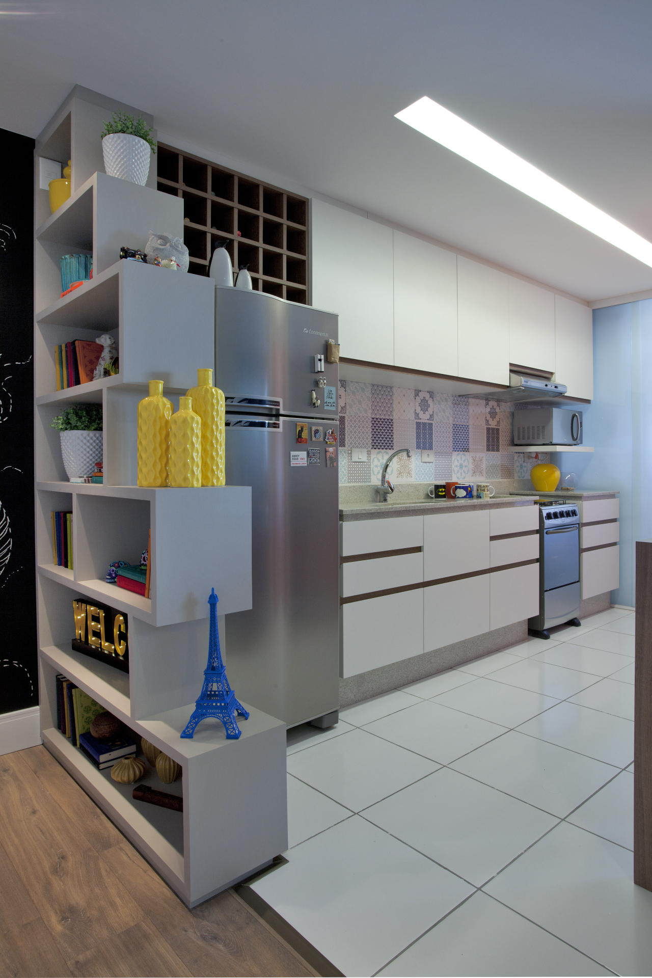 A cozinha é integrada com a área social e  tem cores que conversam com os tons usados na sala.