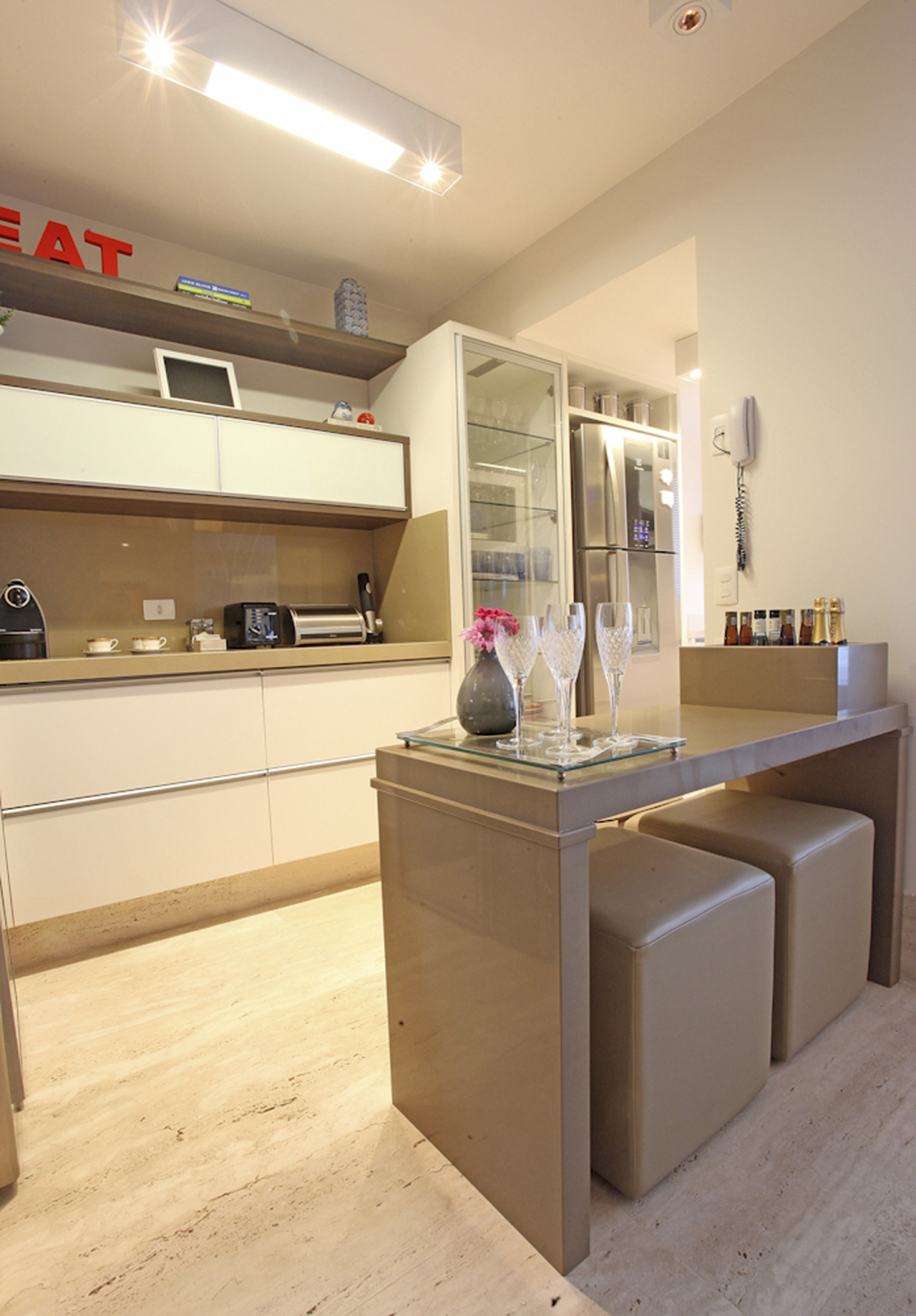 Cozinha integrada: o piso e o mobiliário no mesmo tom da sala dá a ideia de continuidade.