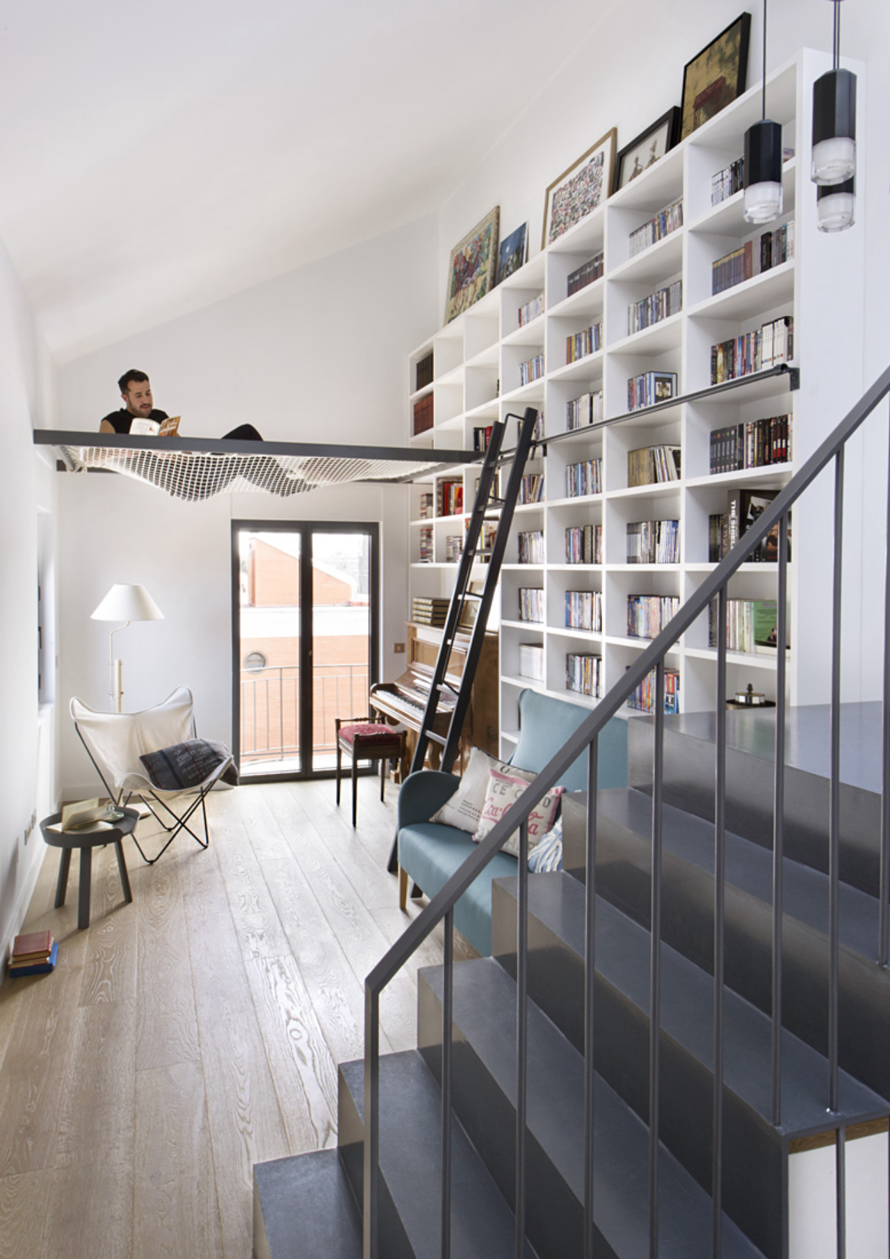 Em estilo moderno, o espaço para leitura do piso até quase o teto ganhou suporte para rede. Foto: Egue &amp; Seta/ Divulgação