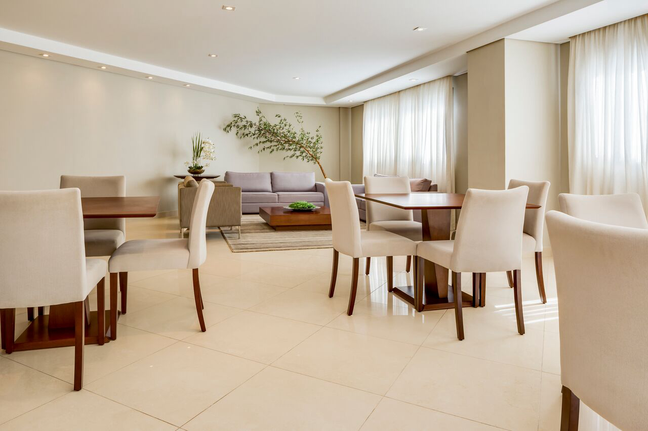 Tons neutros nos pisos e paredes se contrapõem à madeira das cadeiras Sicilia da Momentum &amp; Design. A iluminação pontuada suaviza o ambiente. 