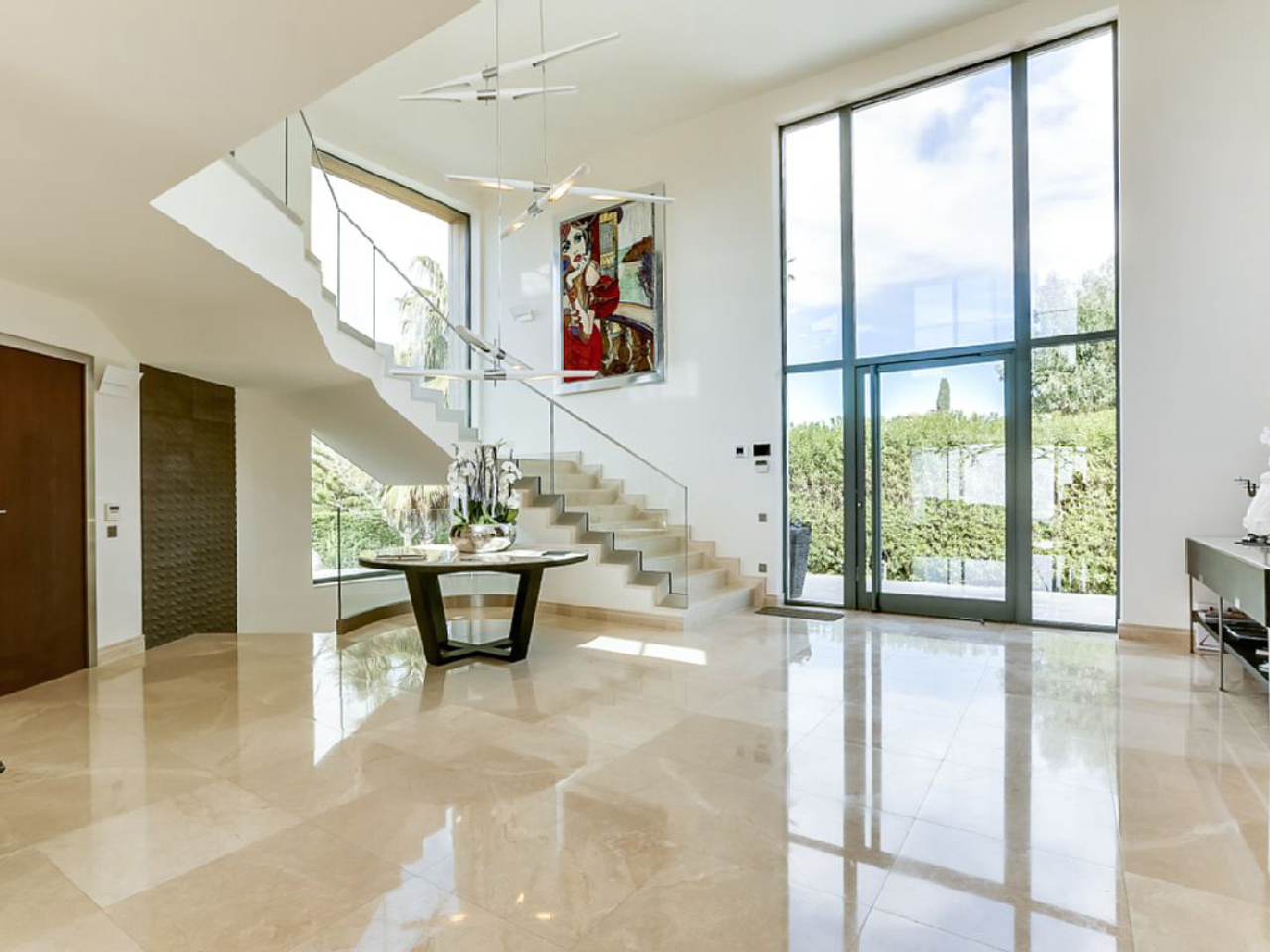 Hall da mansão tem pé direito alto, mármore no piso e uma escada escultural.<br>Foto: Airbnb / Divulgação