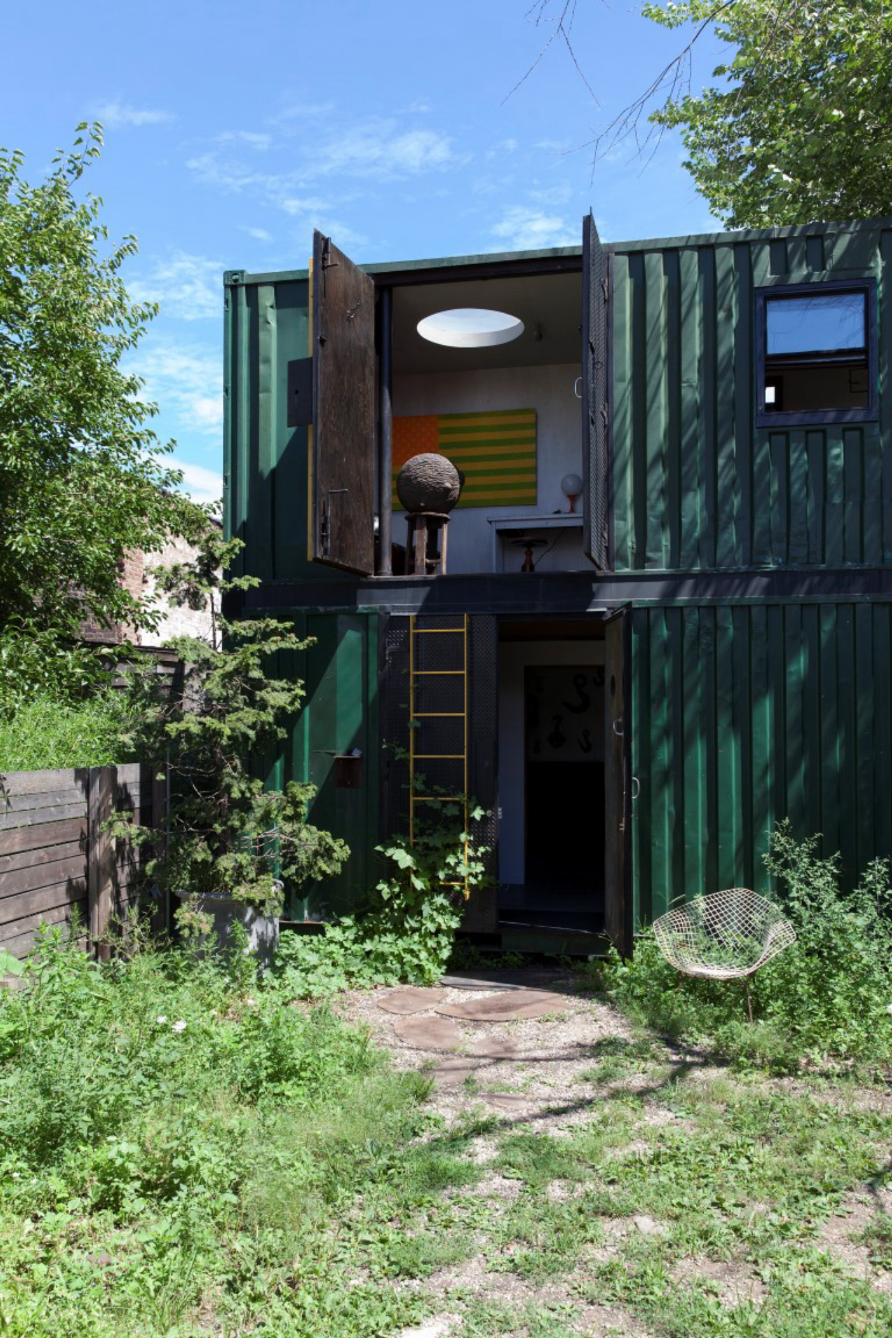 Two of artist Lars Fisk's four shipping containers that make up his home, on a weedy lot he rents in the Red Hook neighborhood of New York, Aug. 17, 2016. The thrifty sculptor of public art, best known for his penchant to playfully render familiar objects as spheres, says he has learned to be economical. (Matthew Johnson/The New York Times)