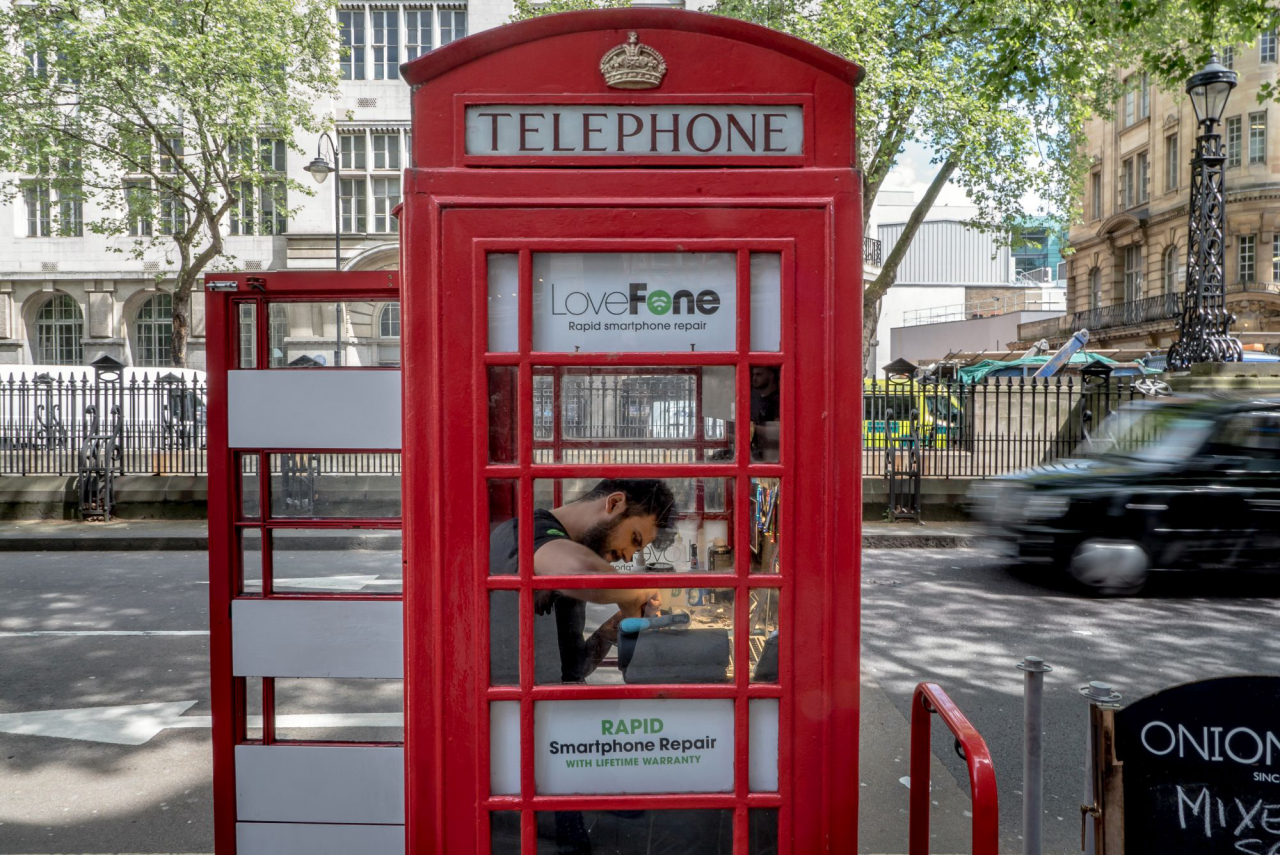 Um homem trabalha na reparação de um telefone celular em uma cabine telefônica restaurada da LoveFone, em Londres. (Foto: Andrew Testa/The New York Times)