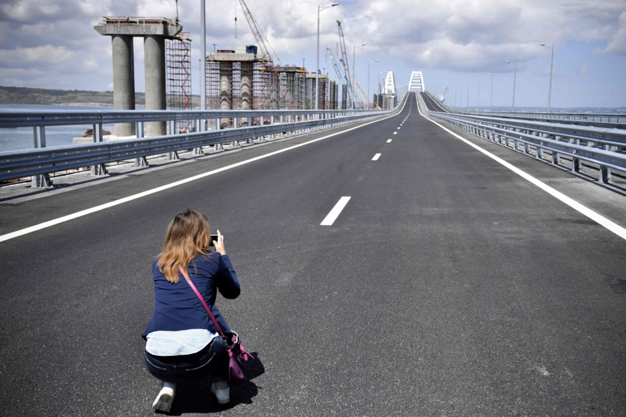 A woman takes a picture prior to the opening ceremony of the 19 km road-and-rail Crimean Bridge passing over the Kerch Strait and linking southern Russia to the Crimean peninsula  on May 15, 2018, in Kerch.<br>Russian President, on May 15 is set to unveil a 19-kilometre-long bridge linking southern Russia to the Crimean peninsula annexed from Ukraine, a highly symbolic project he has personally championed. Built at a cost of 228 billion rubles ($3.69 billion), the new structure connects the southern Krasnodar region with the Crimean city of Kerch, spanning a strait between the Black Sea and the Azov Sea. / AFP PHOTO / POOL / Alexander NEMENOV