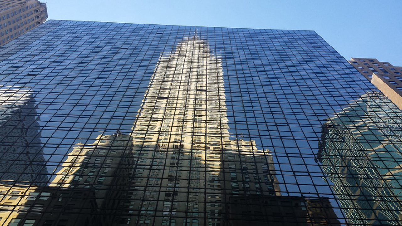 Foto: Chrysler Building refletido em arranha céu moderno.<br>