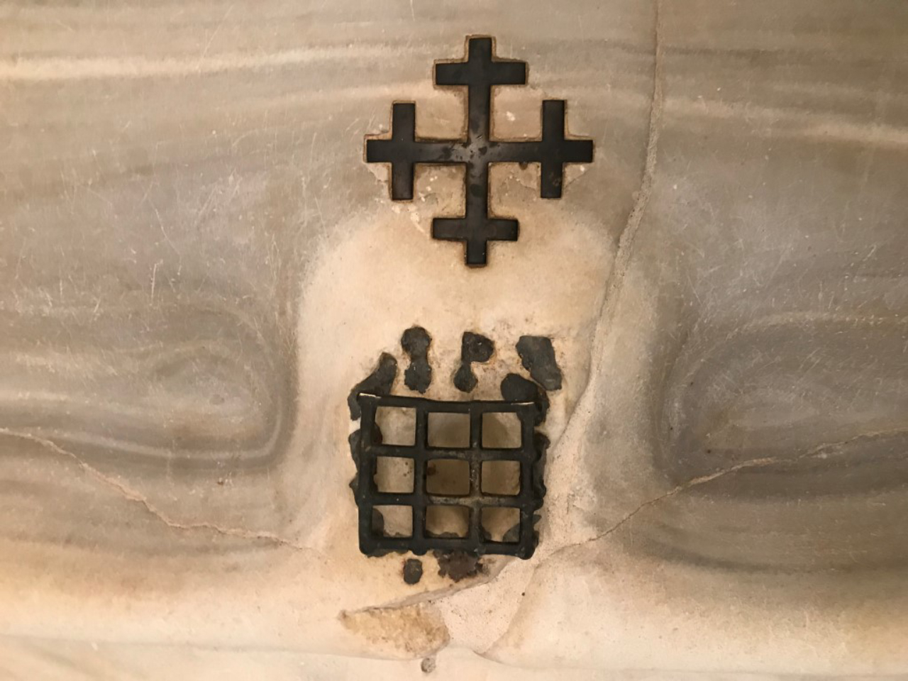A medieval cross and grate set into the marble staircase which Catholic tradition holds Jesus climbed at his judgment before the Roman prefect Pontius Pilate, in Rome, April 8, 2019. The steps, now in a sanctuary across from the Basilica of St. John Lateran, were purportedly brought to Rome in 326 A.D.; the grate covers a spot said to be stained by a drop of Christ's blood. (Elisabetta Povoledo/The New York Times)