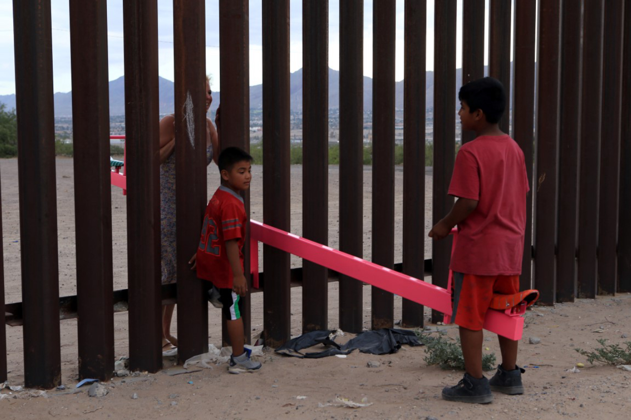 American and Mexican families play with a toy called "up and down" (Seesaw swing) over the Mexican border with US at the Anapra zone in Ciudad Juarez, Chihuahua State, Mexico on July 28, 2019. (Photo by LUIS TORRES / AFP)