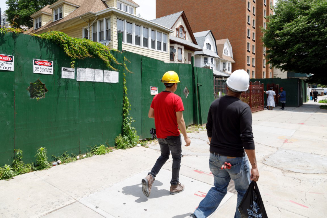 Construction workers walk on June 12, 2019, along a stretch of Lenox Road in the East Flatbush section of Brooklyn which once had a continuous row of one- and two-family houses. Now several of the houses are sitting empty, in preparation for demolition. (Stefano Ukmar/The New York Times)