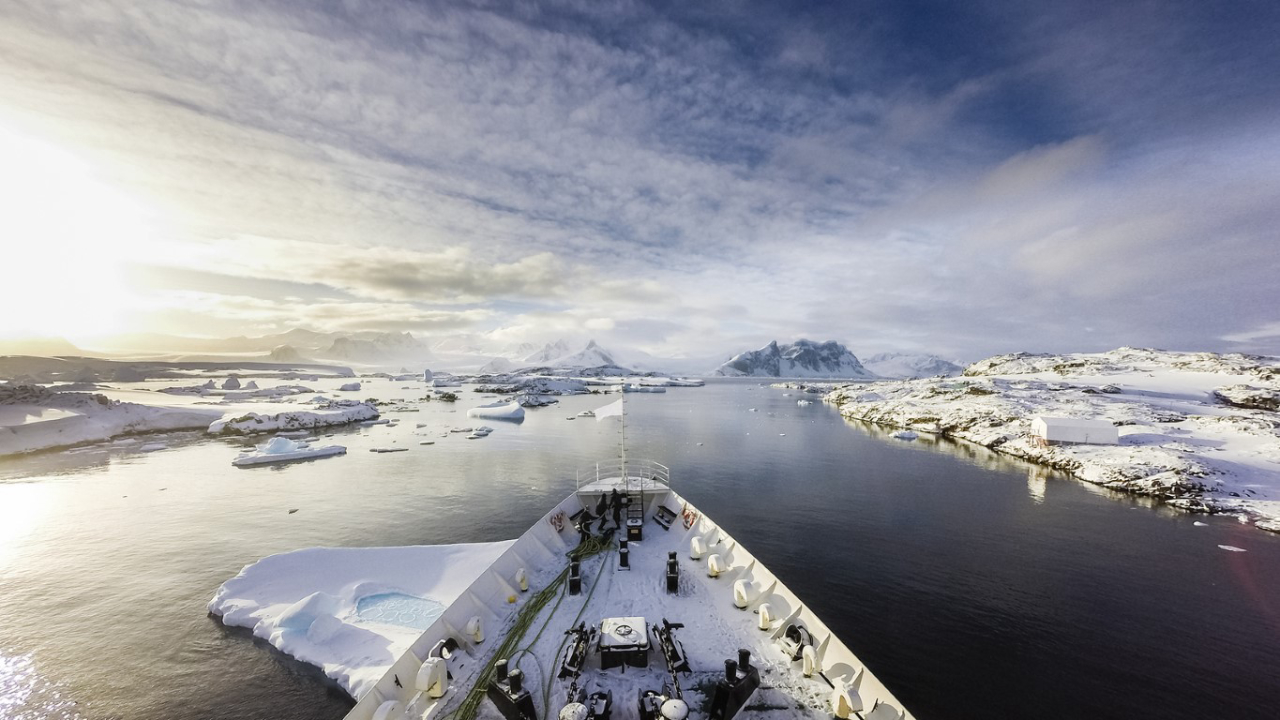 A ship crusing among icebergs  between frozen land of Antarctica and islands surrounding it