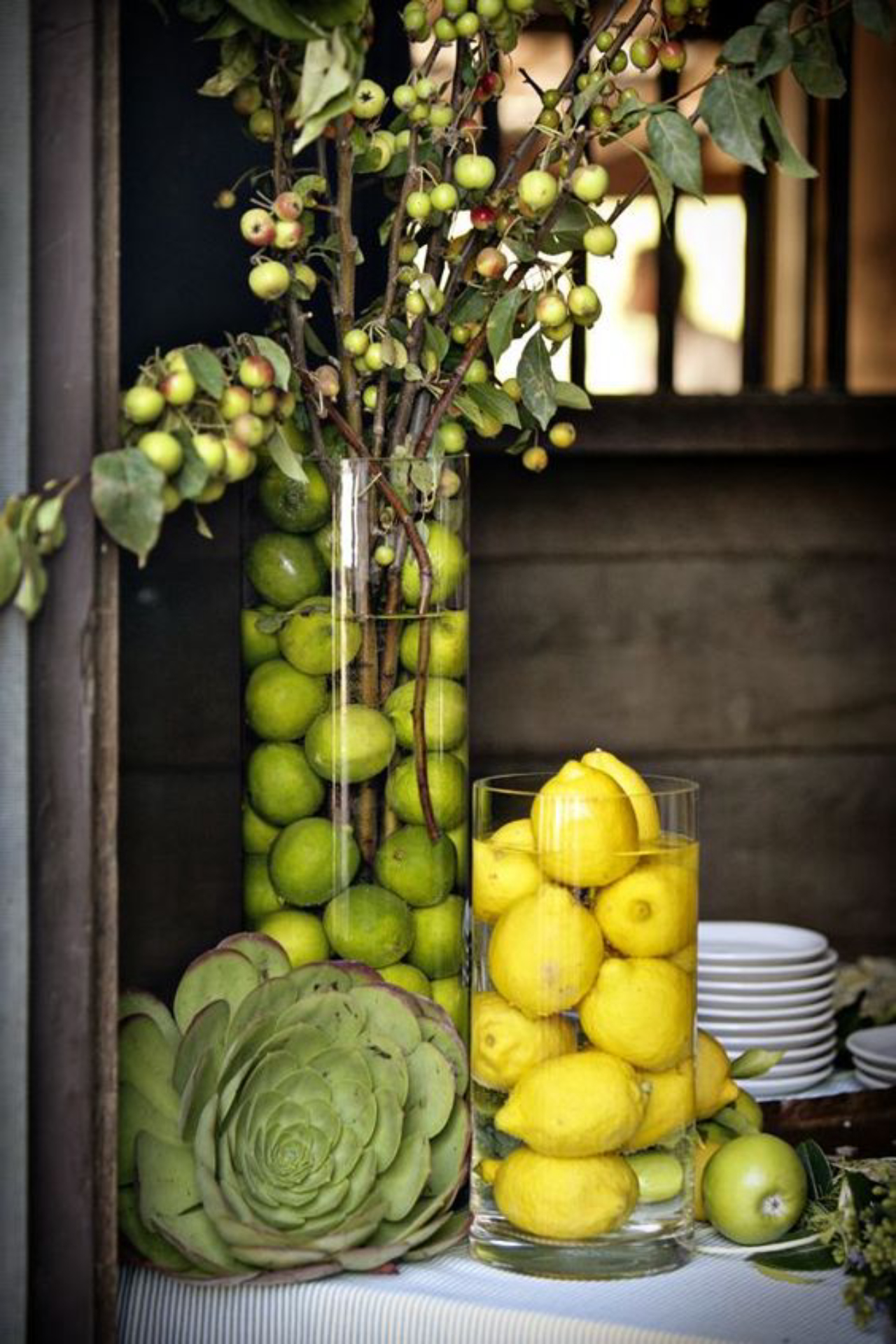 Galhos com frutas podem ser colocados em vasos com água para formar enfeites de mesa. Para deixar o arranjo ainda mais bonito, coloque limões inteiros na água. Foto: Pinterest/Reprodução