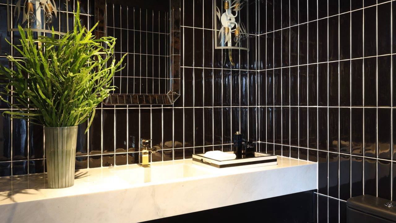 No banheiro, azulejos pretos contrastam com a bancada em mármore branco.
