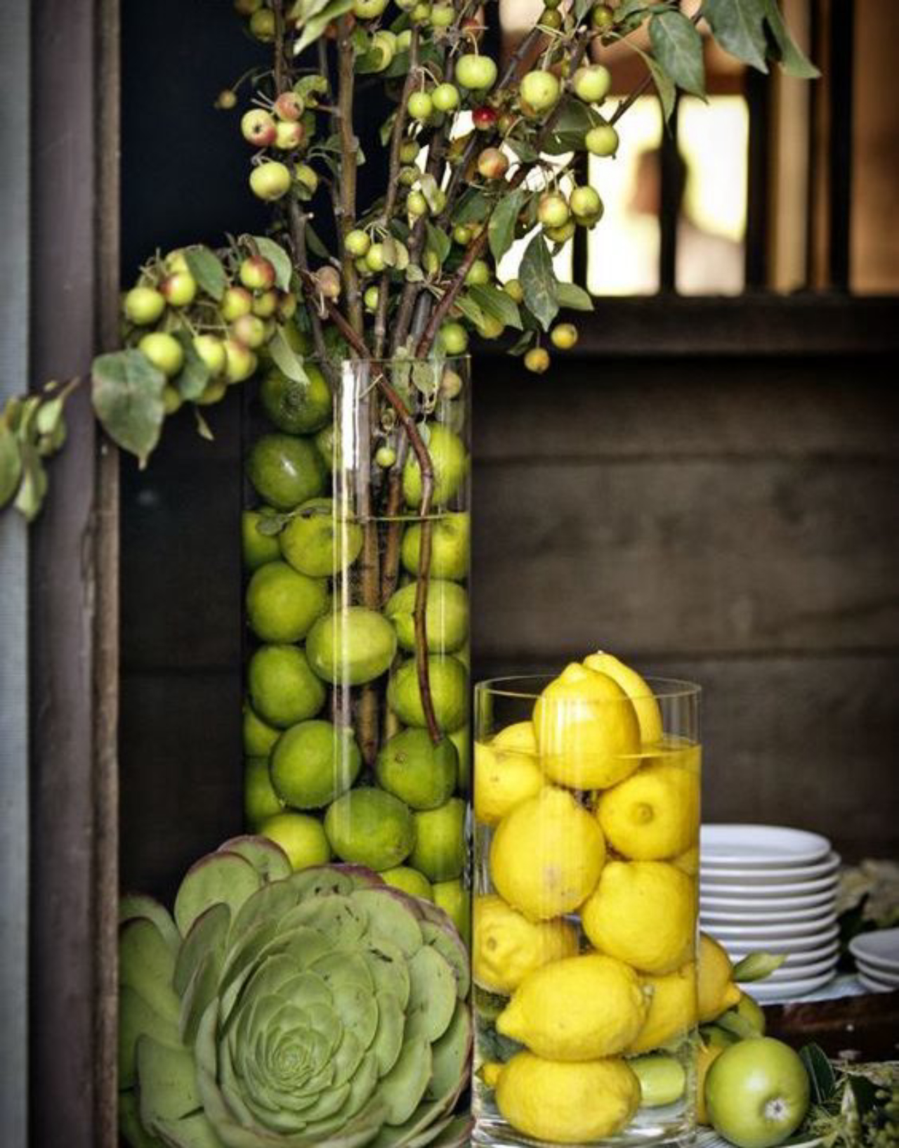 Galhos com frutas podem ser colocados em vasos com água para formar enfeites de mesa. Para deixar o arranjo ainda mais bonito, coloque limões inteiros na água. Foto: Pinterest/Reprodução