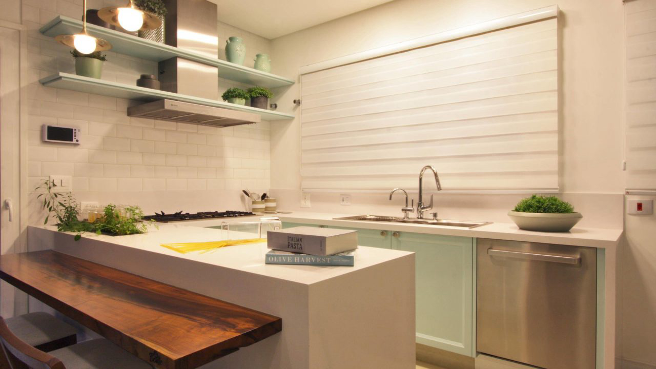 Cozinha projetada por Laryssa Rocha recebeu bancada de pedra Silestone branca, com parte em madeira, que serve tanto para dividir os ambientes, como para refeições rápidas.