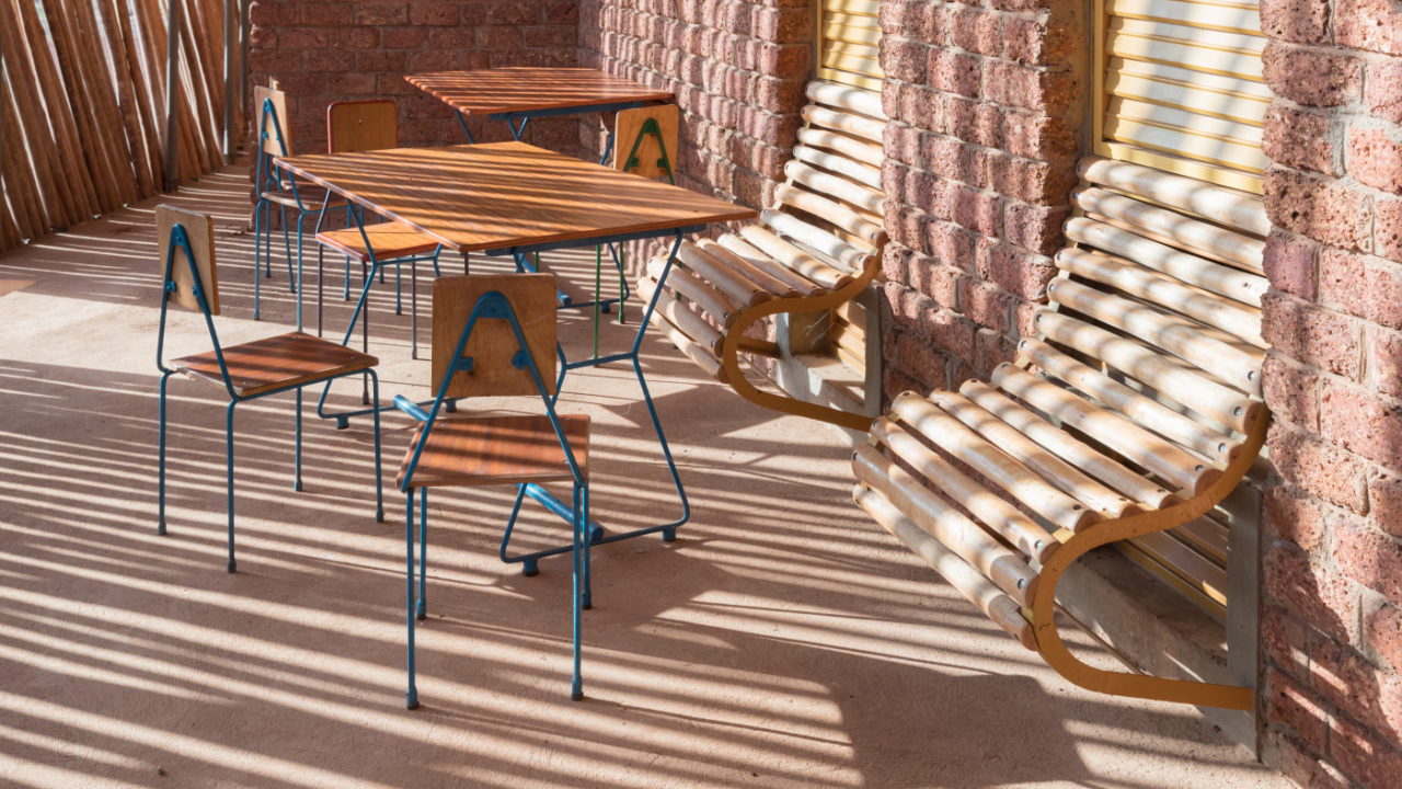Detalhe das mesas e cadeiras criadas com materiais da região, e dos bancos de madeira que surgem das janelas.