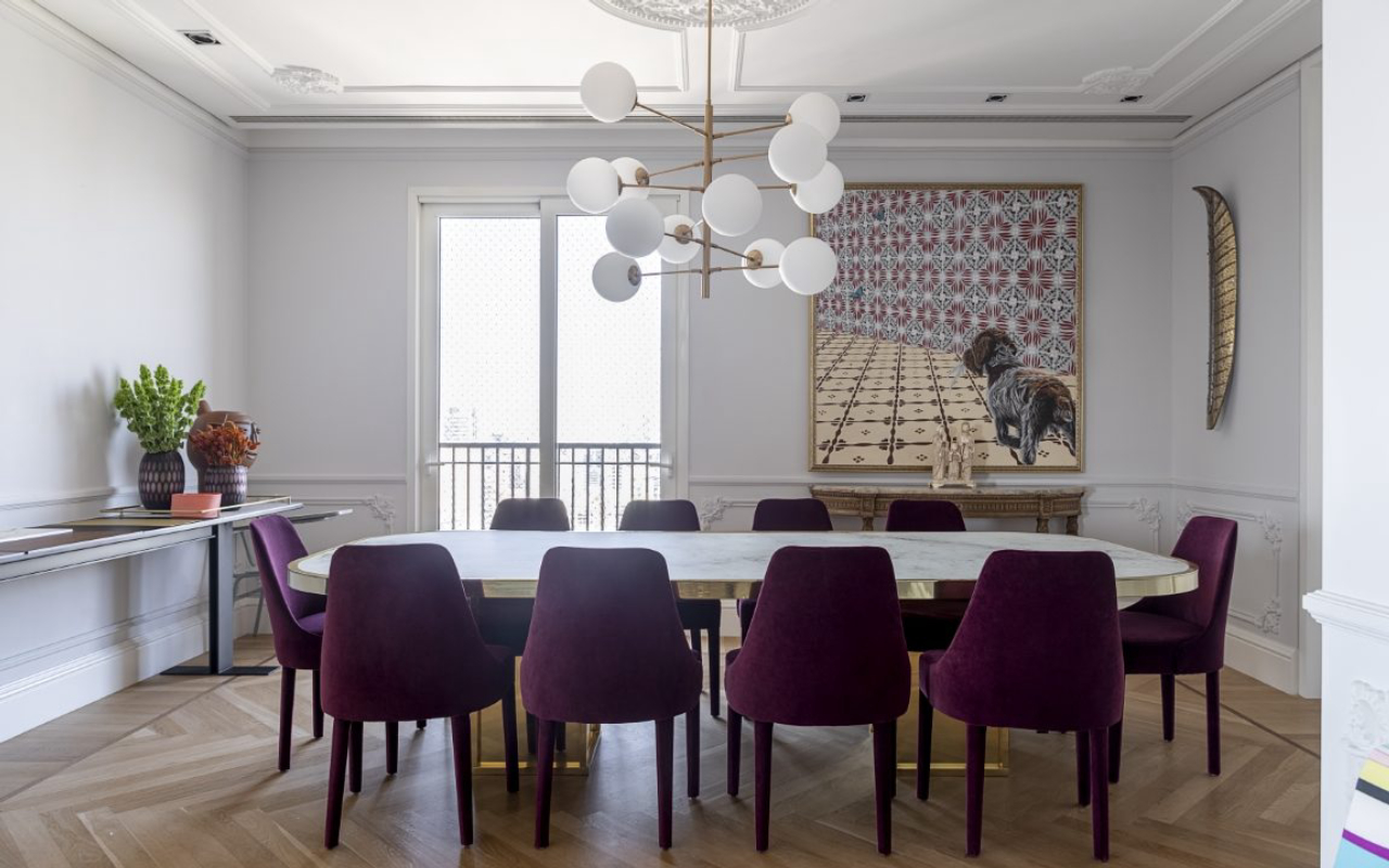 A mesa de jantar foi desenhada pelo escritório Bárbara Jalles Guimarães; as cadeiras de veludo roxo trazem peso ao ambiente.