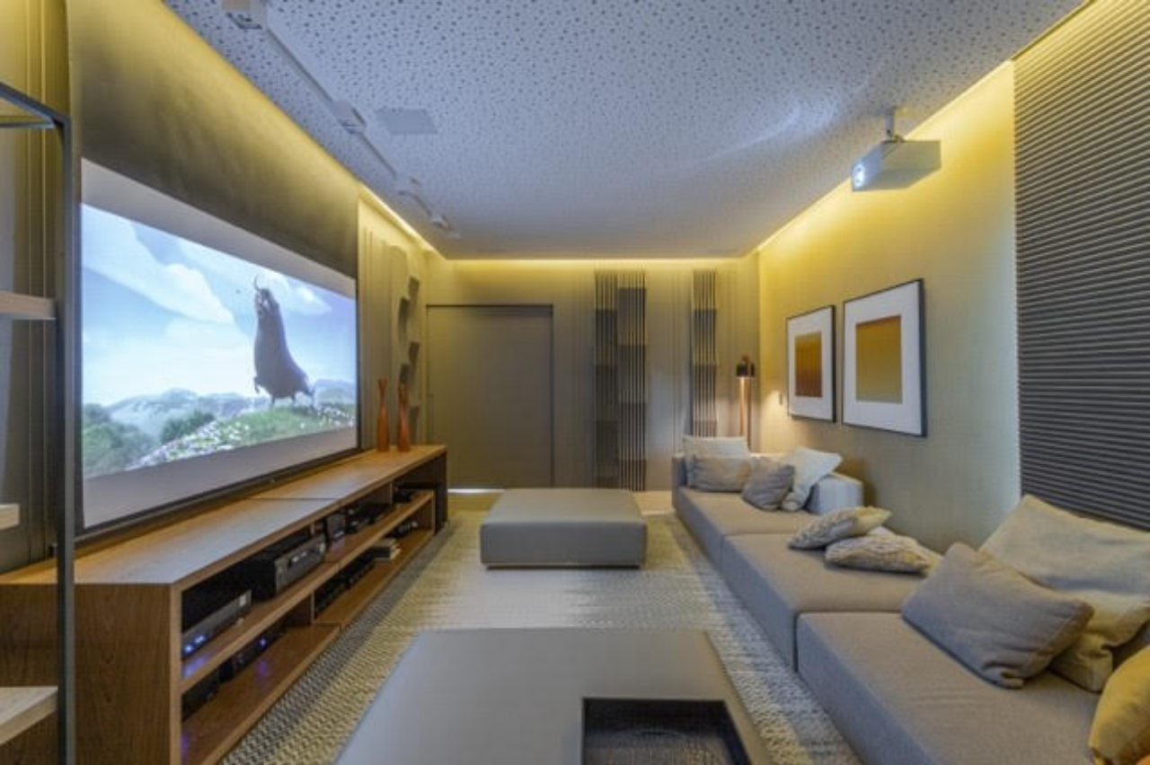 Neste projeto de Patrícia Penna Arquitetura &amp; Design de Interiores, a iluminação lateral no teto torna a luz indireta no cômodo e não interfere refletindo na tela do televisor