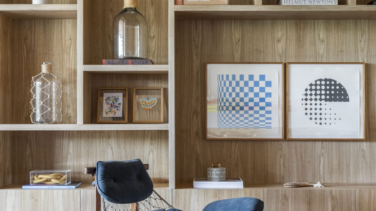 A poltrona Jangada, de Jean Gillon, compõe a sala de estar do piso térreo, na qual uma estante em madeira valoriza o ambiente com diversos objetos decorativos.