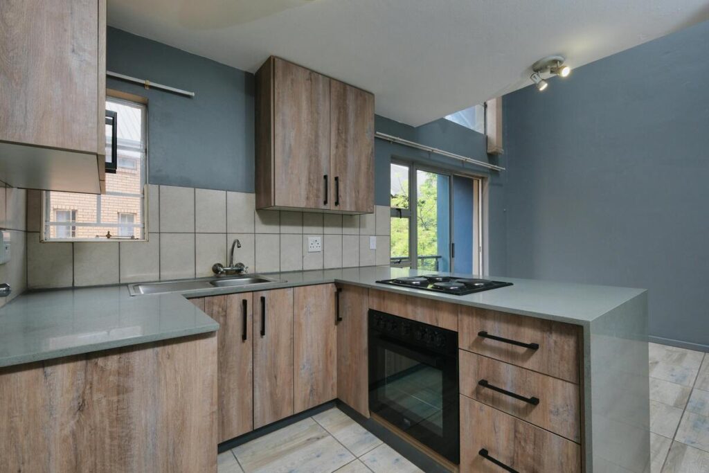 Contraste marcante: o calor da madeira rústica dos armários é equilibrado pela profundidade e elegância do azul-petróleo na parede, uma excelente paleta que adiciona sofisticação e mistério a cozinhas contemporâneas. Fonte: Pexels